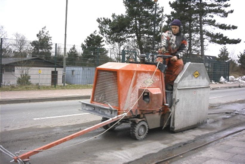 A man in work clothes is riding on a machine and working on the