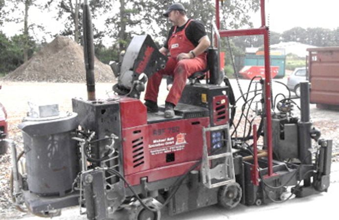 Ein Mitarbeiter in Arbeitskleidung auf einer Maschine beim Grooving und Grinding