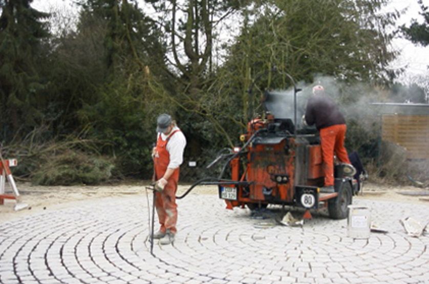 Bilder bei der Einarbeitung des Pflasterverguss von Mitarbeitern mit Maschinen