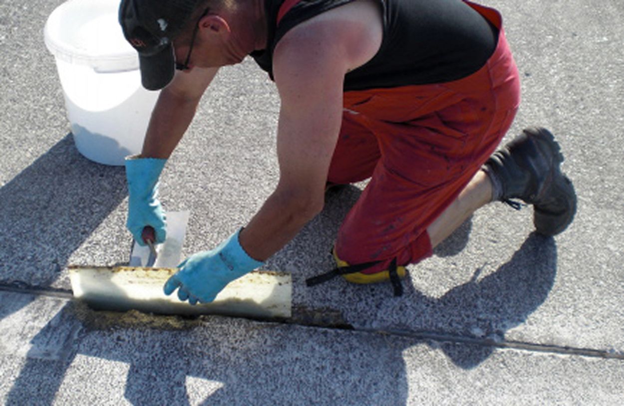 An employee in work clothes repairs road damage with the fast-curing repair system